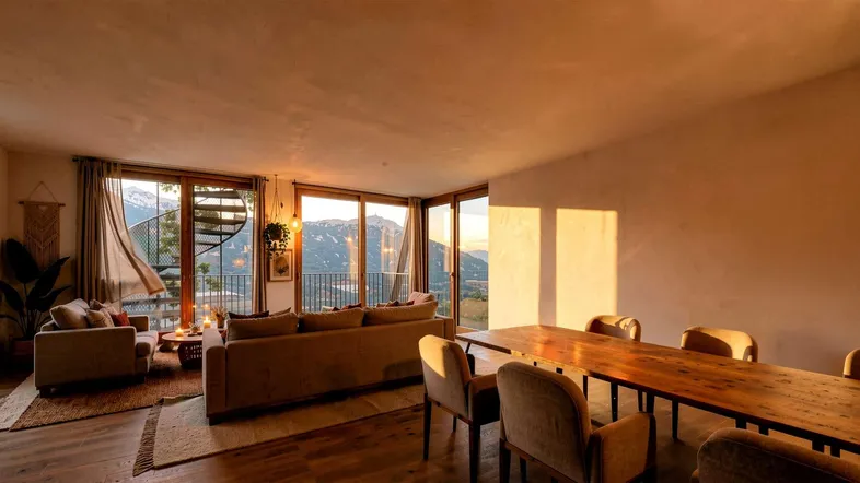 Heller Wohn- und Essbereich mit großen Fenstern, Bergblick und gemütlichem Kamin.
