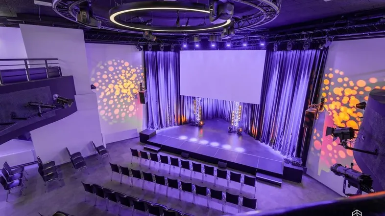 Großer Veranstaltungsraum mit Bühne, Leinwand und Reihenbestuhlung, ideal für Konferenzen oder Aufführungen.