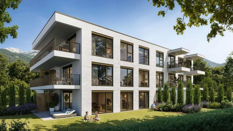 Moderne Wohnanlage mit weißen Fassaden, Balkonen und einem Gartenbereich vor Bergkulisse.