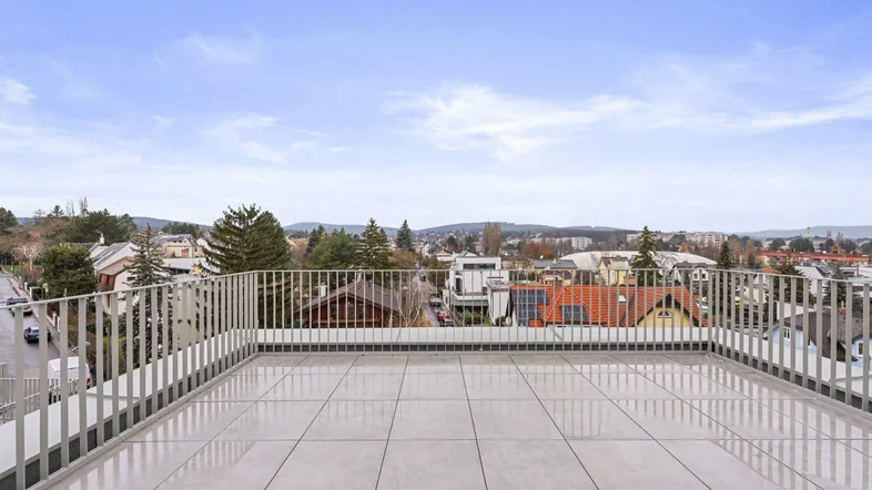 Geräumige Dachterrasse mit hellen Fliesen und weitem Blick über die Stadt und die umliegende Landschaft.