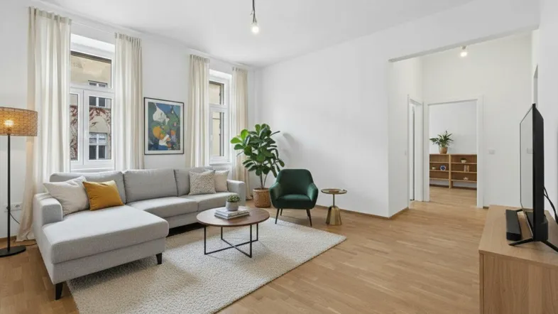Helles und modern eingerichtetes Wohnzimmer mit hohen Decken, Parkettboden und großen Fenstern.