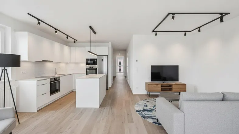 Moderne offene Küche und Wohnbereich mit Holzboden, weißer Einbauküche und stilvoller Beleuchtung.