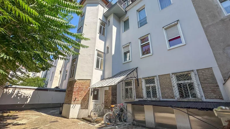 Ansicht der Gebäudefassade mit einem Innenhof, Fahrradstellplätzen und einem kleinen Balkon.