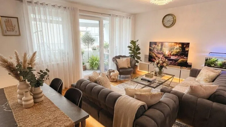 Gemütlicher offener Wohn- und Essbereich mit Holzboden, bequemen Sofas und Zugang zum Balkon.