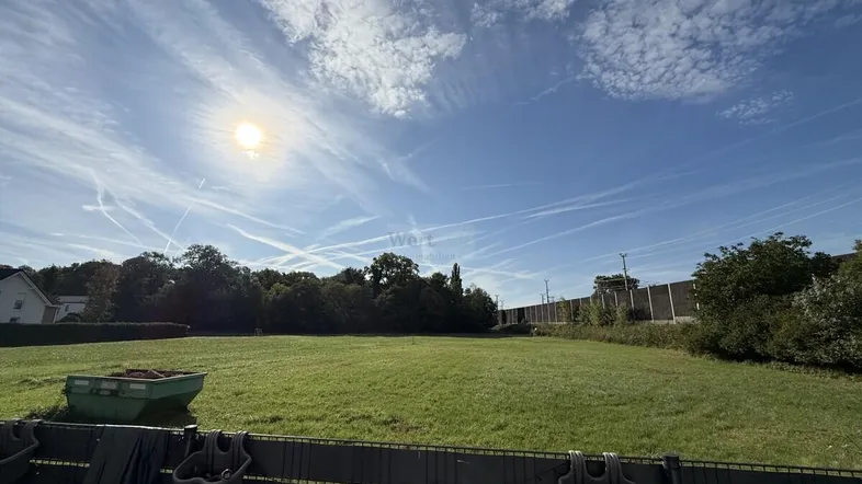 Weitläufige Rasenfläche unter blauem Himmel mit Sonnenschein, ideal für Freizeitaktivitäten im Freien.