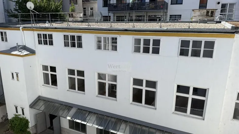 Ansicht der Rückseite eines Gebäudes mit mehreren Fenstern und einem Flachdach.