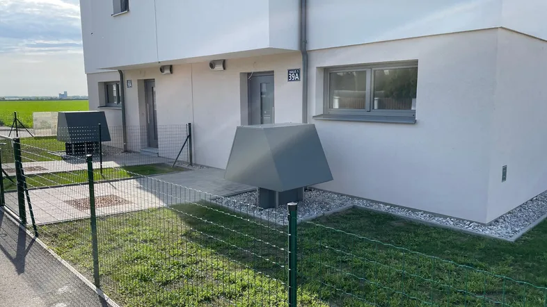 Moderne Reihenhäuser mit kleinen Vorgärten und effizienten Wärmepumpen im Außenbereich.
