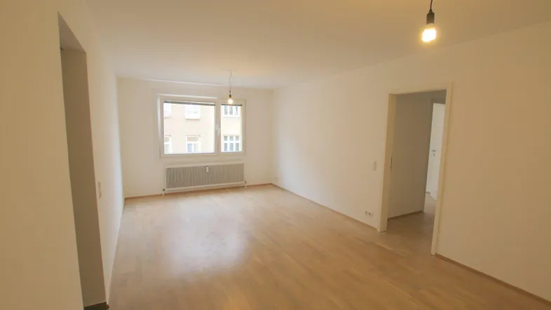 Helles, leeres Zimmer mit Parkettboden und Fenster, bereit zur individuellen Gestaltung.