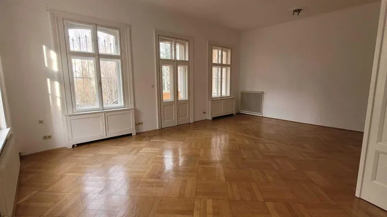 Helles Zimmer mit Fischgrätparkettboden und hohen Fenstern, bereit zur Einrichtung.
