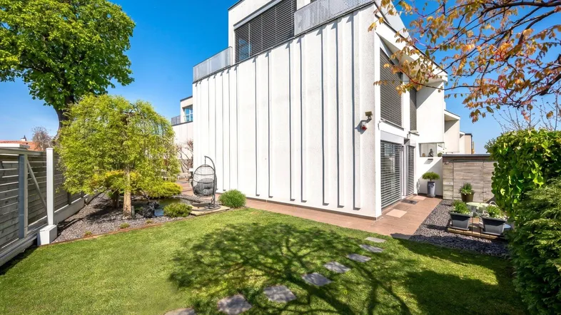 Moderne Gebäudefassade mit gepflegtem Rasen und Trittsteinen im Gartenbereich.