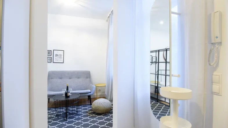 Heller Eingangsbereich mit großem Spiegel, der in ein gemütliches Wohnzimmer mit Sofa führt.