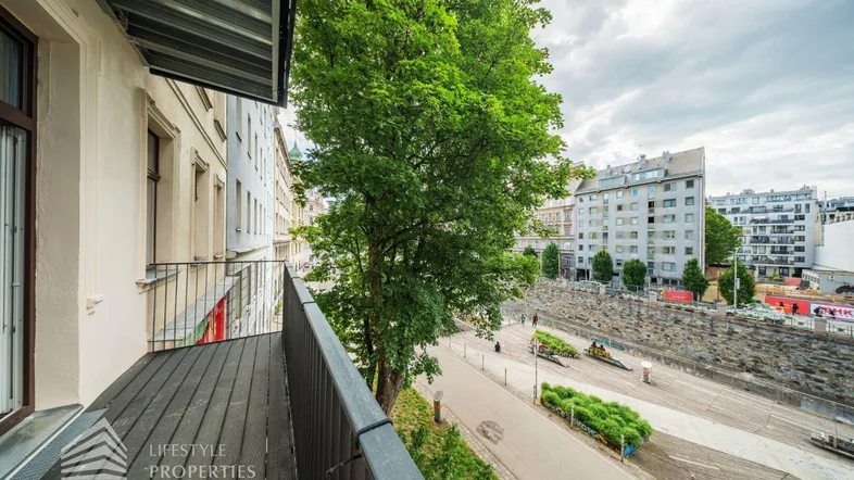 Balkon mit Blick auf die Straße, umliegende Gebäude und viel Grün.