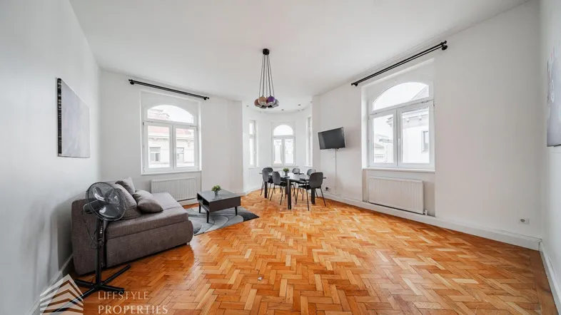Helles Wohn- und Esszimmer mit Fischgrätparkett und großen Fenstern, modern eingerichtet.