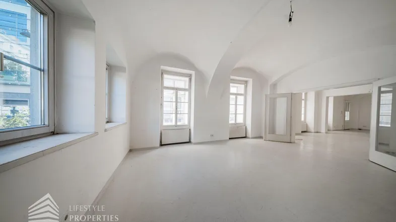 Geräumiger, leerer Wohnbereich mit hohen Gewölbedecken und großen Fenstern, bereit zur individuellen Gestaltung.