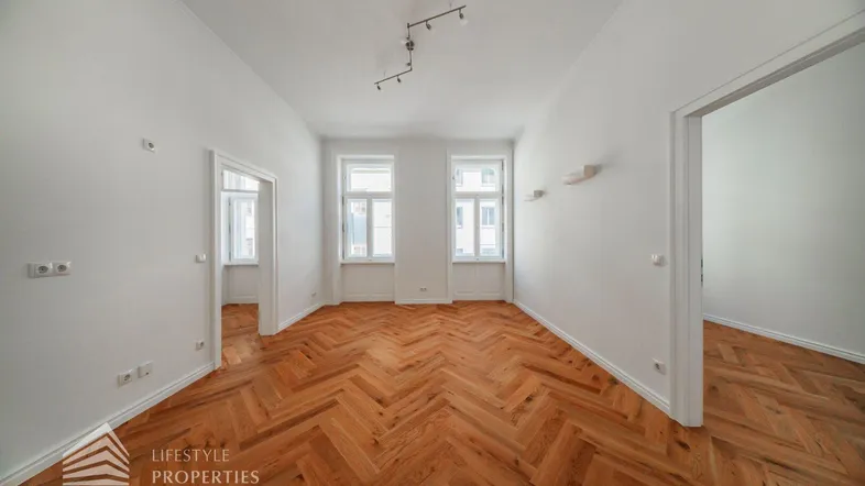 Helles, leeres Zimmer mit Fischgrätparkett und hohen Decken, bereit zur individuellen Gestaltung.