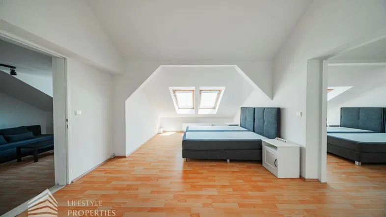 Helles Schlafzimmer im Dachgeschoss mit zwei Betten, Holzfußboden und Dachfenstern.