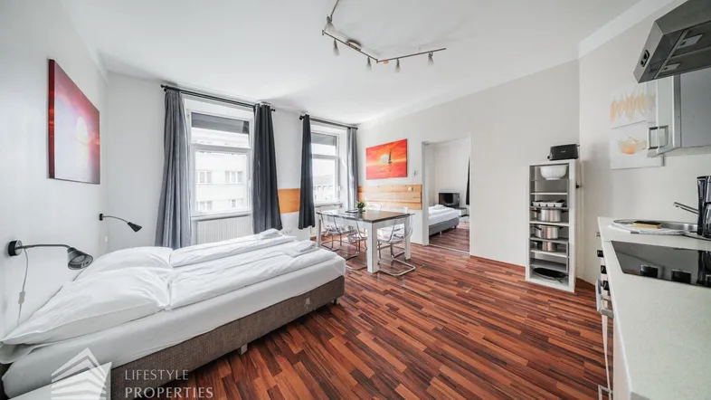 Helles Studio-Apartment mit Schlafbereich, Esstisch und integrierter Küchenzeile, ideal für modernes Wohnen.