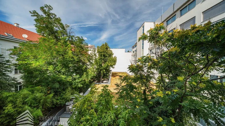 Blick auf begrünte Dächer und umliegende Gebäude unter blauem Himmel.