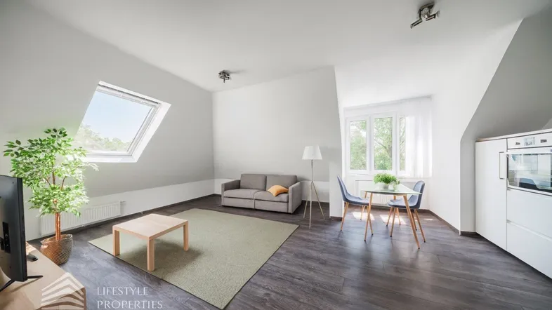 Helles Wohn- und Esszimmer im Dachgeschoss mit Holzboden, Dachfenster und moderner Einrichtung.