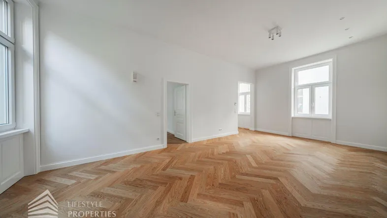 Heller Raum mit elegantem Fischgrätparkett und hohen Fenstern, ideal für Wohn- oder Essbereich.
