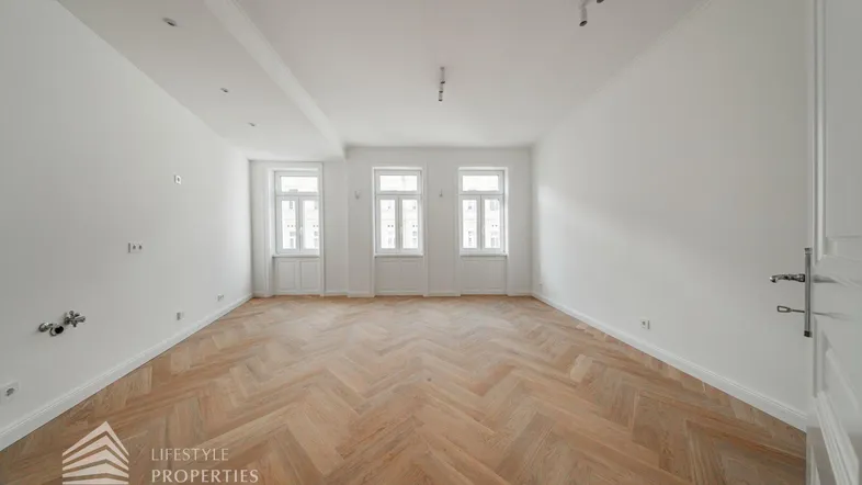 Helles Zimmer mit Fischgrätparkett und drei großen Fenstern, ideal für Wohn- oder Essbereich.