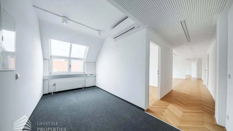 Heller Büroraum im Dachgeschoss mit Teppichboden, Dachfenstern und Klimaanlage.