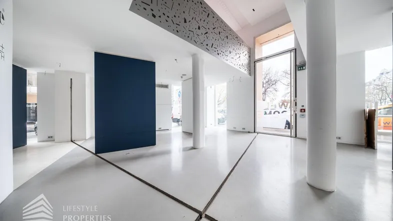 Geräumiger, heller Gewerberaum mit hohen Decken, großen Fenstern und modernem Betonboden.