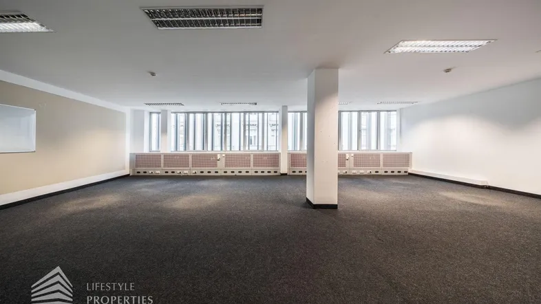 Geräumiger, leerer Büroraum mit Teppichboden und großen Fenstern, bereit zur individuellen Gestaltung.
