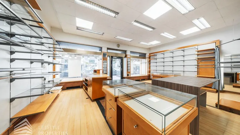 Heller Verkaufsraum mit Holzfußboden, Regalsystemen und großen Schaufenstern zur Straße.