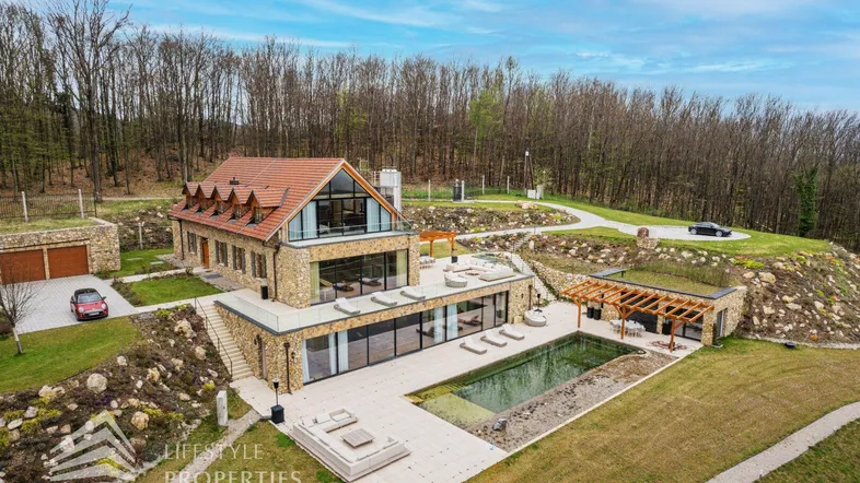 Luxuriöses Anwesen mit weitläufigem Grundstück, Pool und moderner Architektur in hügeliger Landschaft.