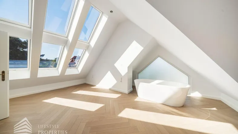 Helles Dachgeschosszimmer mit freistehender Badewanne und vielen Dachfenstern für viel Tageslicht.