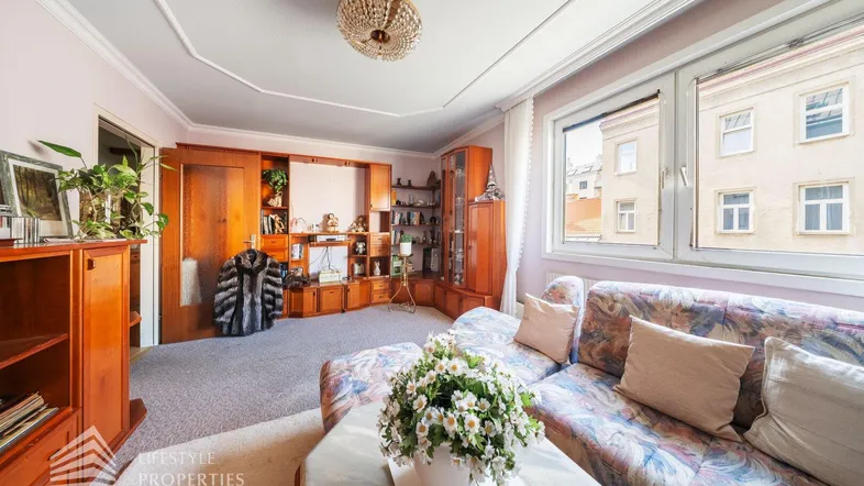 Gemütliches Wohnzimmer mit großem Sofa, Teppichboden und Blick auf die Stadt.