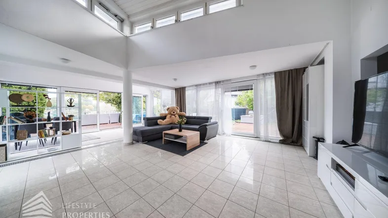 Helles und geräumiges Wohnzimmer mit Fliesenboden, hohen Decken und Zugang zur Terrasse.