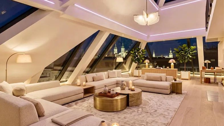 Großzügiges Wohnzimmer mit schrägen Glasdächern, Stadtblick und moderner Beleuchtung bei Nacht.