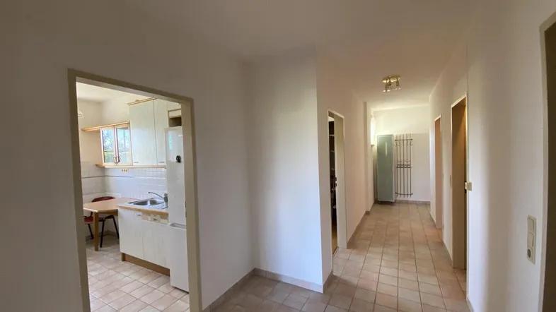 Heller Flur mit Fliesenboden und Blick in die angrenzende Küche, gut gepflegt.