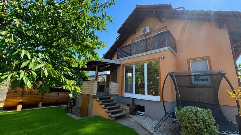 Außenansicht des Hauses mit gepflegtem Rasen, Trampolin und überdachtem Sitzbereich im Garten.