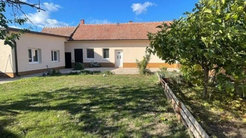 Geräumiger Gartenbereich mit Rasenfläche und Blick auf das Haus unter blauem Himmel.