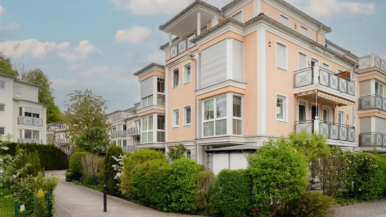 Mehrfamilienhaus mit moderner Architektur, Balkonen und gepflegter Außenanlage.