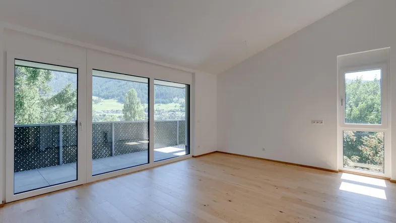 Helles Wohnzimmer mit Holzboden, großen Fenstern und Zugang zu einem Balkon mit Bergblick.