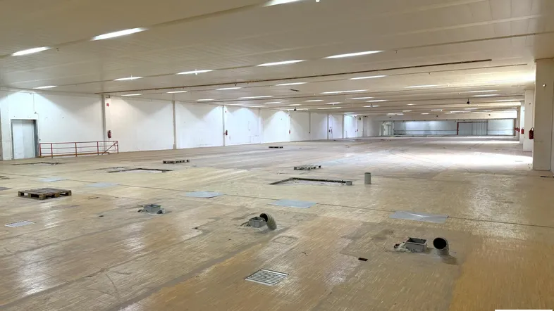 Große, helle Lagerhalle mit glattem Boden und moderner Beleuchtung, bereit für die Nutzung.