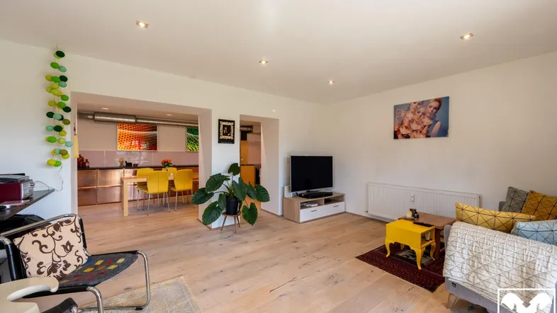 Helles Wohnzimmer mit Holzboden, moderner Einrichtung und offenem Übergang zum Essbereich.