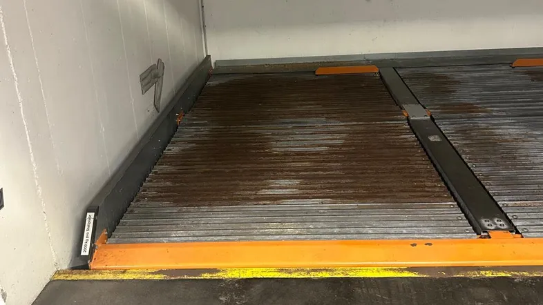 Innenansicht eines Parkplatzes mit mechanischem Doppelparker-System in einer Tiefgarage.