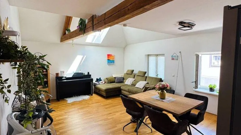 Helles, offenes Wohn- und Esszimmer mit Holzbalken, Parkettboden und Dachfenstern.