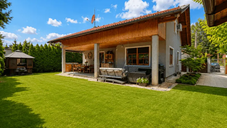 Haus mit großem Garten und überdachter Terrasse, ideal für Entspannung im Freien und Grillabende.