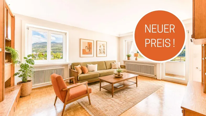 Helles Wohnzimmer mit bequemer Couch, Holzboden und Blick auf die grüne Landschaft.