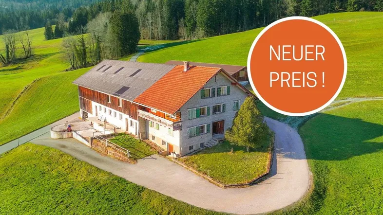 Ländliches Anwesen mit großem Gebäude und weitläufigen grünen Wiesen in bergiger Landschaft.