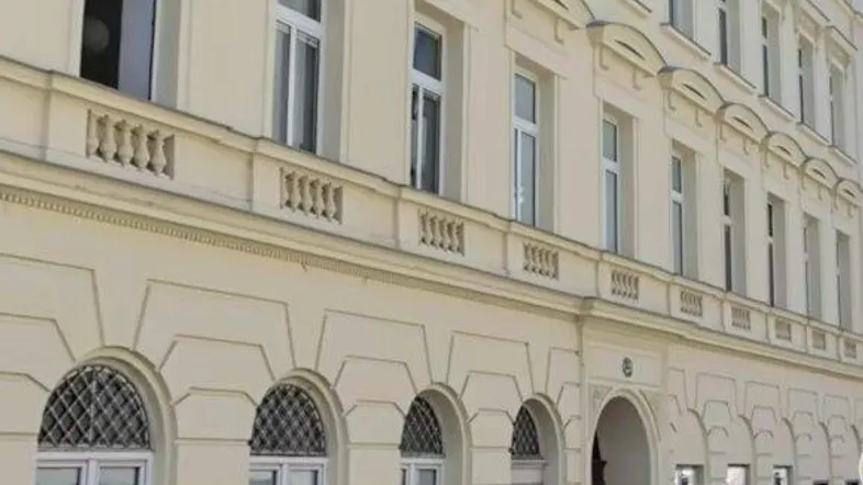 Klassisches Mehrfamilienhaus mit heller Fassade und vielen Fenstern an einer Stadtstraße.