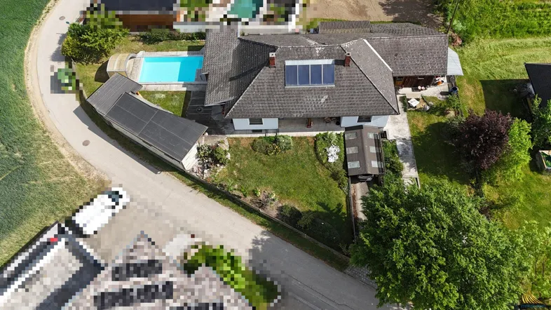 Luftaufnahme eines Hauses mit Pool, Garten und Photovoltaikanlage auf dem Dach.