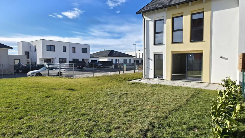 Neubau-Doppelhaushälfte mit frisch angelegtem Rasen und sonnigem Gartenbereich.