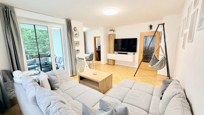 Helles Wohnzimmer mit großem Sofa, Holzboden und Zugang zum Balkon, ideal zum Entspannen.